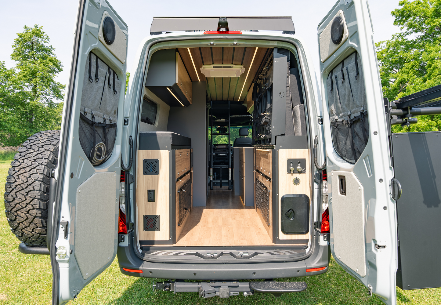 Rear view of Sprinter van with Highland Vans Murphy Bed and utility cabinets installed, showcasing modular camper layout