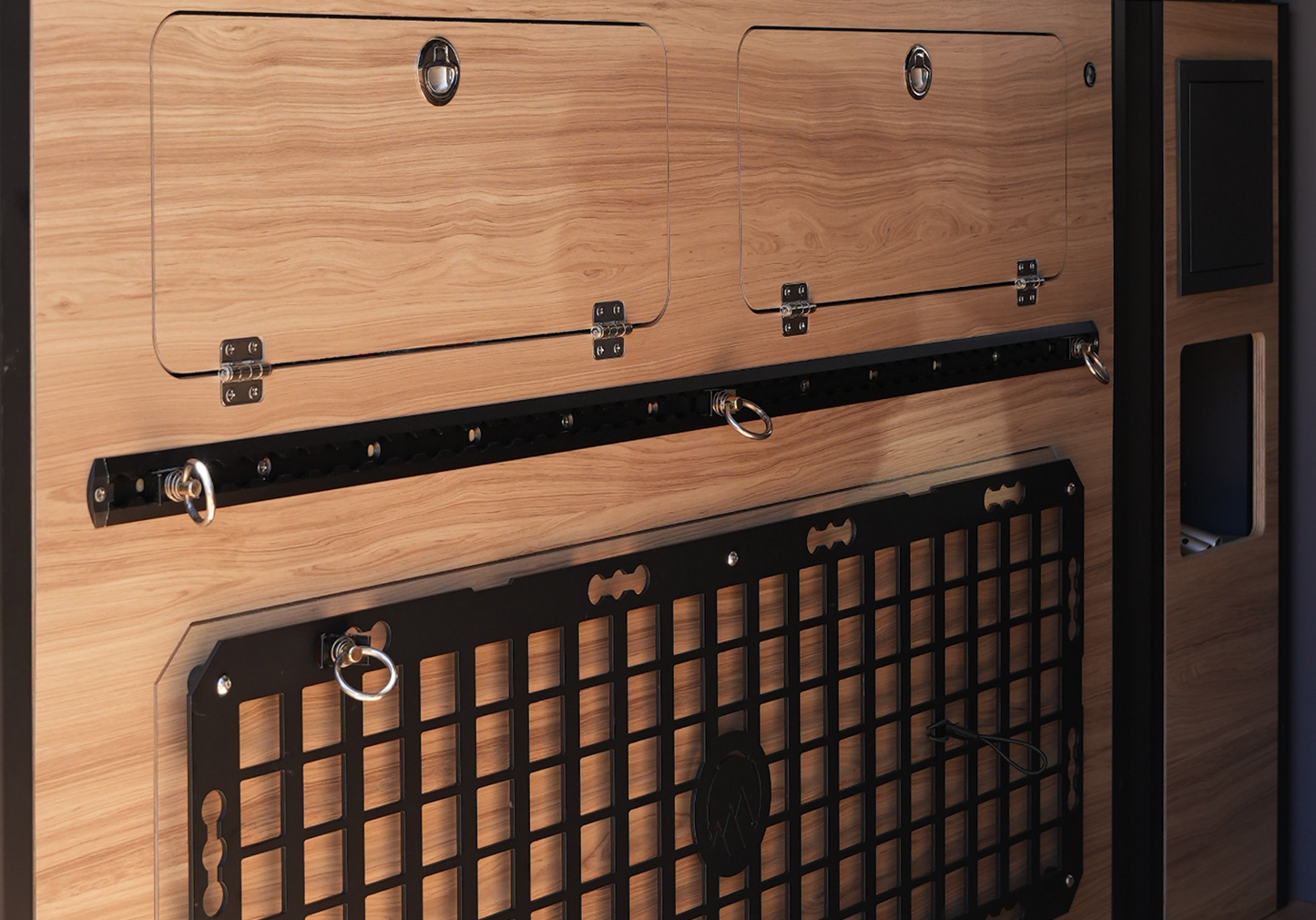 Close-up of MOLLE panel and L-track system in Highland Vans Murphy Bed setup, black aluminum mounting grid for gear